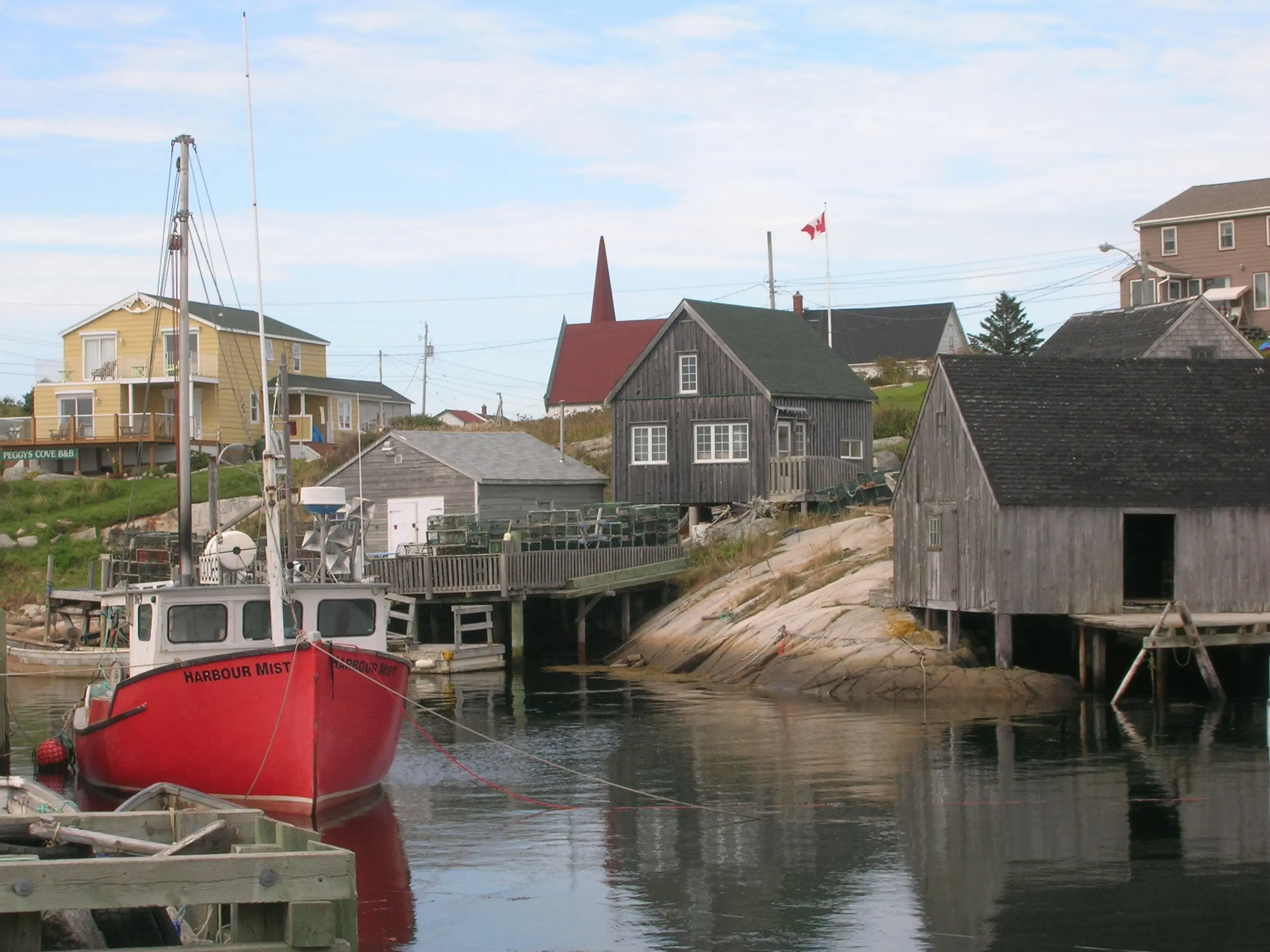 Red and white boat on dock during daytime in Peggy’s Cove NS.